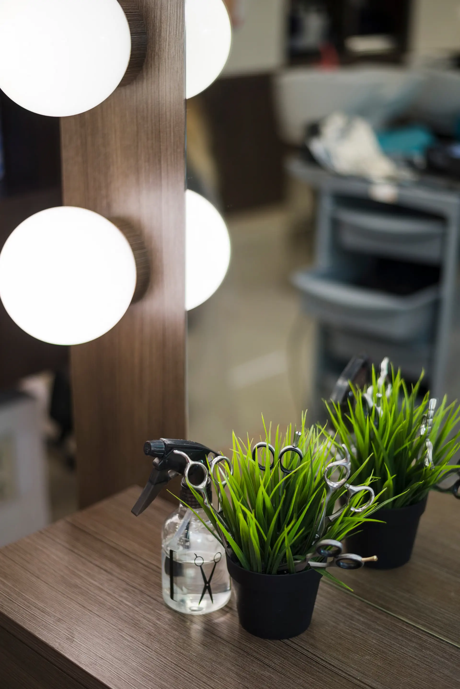 Stanowisko fryzjerskie z lustrem i oświetleniem, nożyczkami oraz akcesoriami do stylizacji włosów